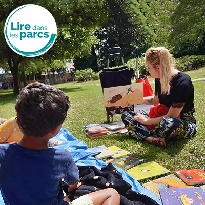 Personne lisant un album jeunesse à des enfants dans un parc
